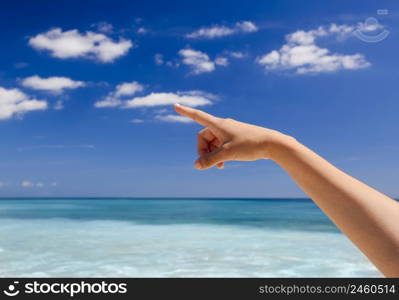 Female hand against a beautiful blue sky pointing somewhere