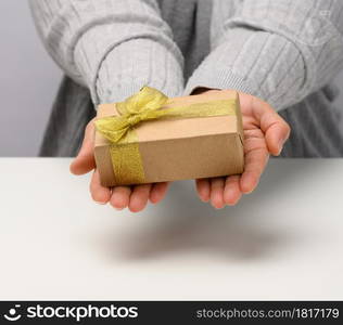 female hand are holding a gift box on a gray background, happy birthday concept, close up