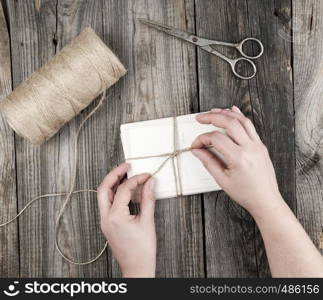 female hand bandages stack of cards with brown rope on a gray wooden table, top view