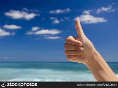 Female hand doing thumbs up against a beautiful blue sky