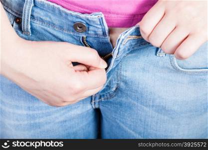 female hand fastens jeans zipper close up