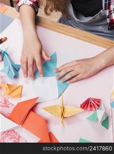 female hand folding paper while making decorative origami art craft