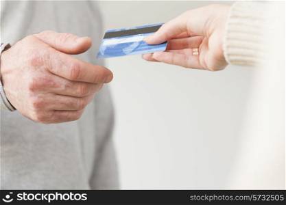 Female hand giving a plastic card to senior male hand