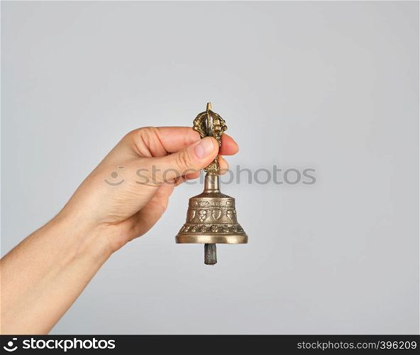 female hand holding a bronze bell for alternative medicine, meditation and relaxation