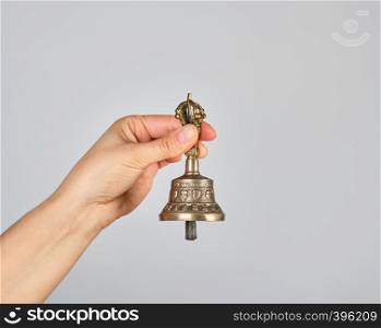 female hand holding a bronze bell for alternative medicine, meditation and relaxation