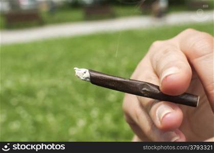 Female hand holding a lighted hand-rolled cigarette