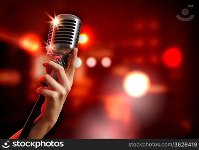 Female hand holding a single retro microphone against colourful background