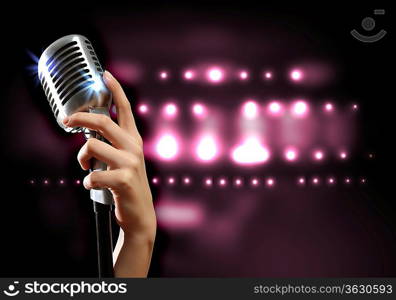 Female hand holding a single retro microphone against colourful background