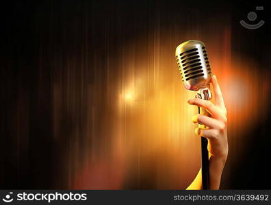 Female hand holding a single retro microphone against colourful background