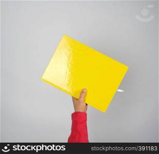 female hand holding a yellow notebook on a gray background