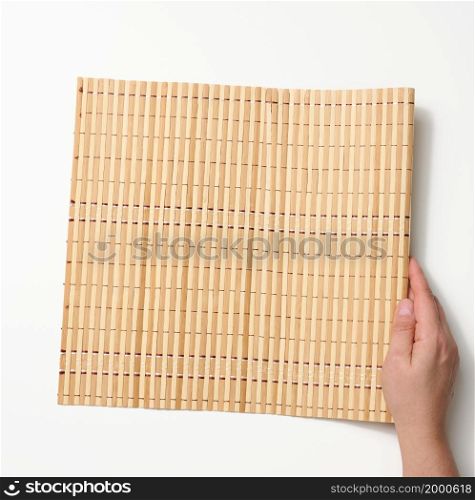 female hand holding bamboo mat on white background