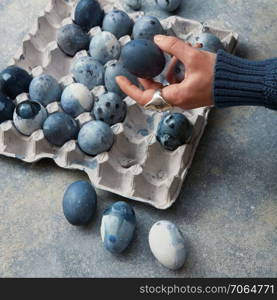 Female hand holding Easter eggs. Workspace with easter decoration.. Eggs in paper tray