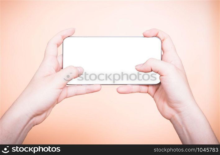 Female hand holding mobile smartphone play game gamer blank white screen on orange background