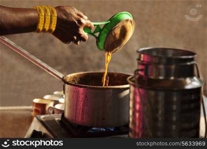 Female hand holding strainer while preparing chai