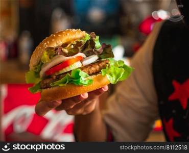 Female hand holding tasty beef burgers. Hamburger or Burger, food concept.