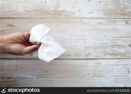 Female hand holding tissue on wooden background top view with copy space, hygienic clean concept space for text. Female hand holding tissue on wooden background top view with copy space, hygienic clean concept