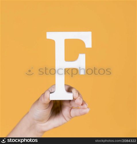 female hand holding up uppercase capital letter f