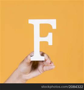 female hand holding up uppercase capital letter f