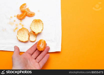 female hand holding white clothes with ditry stains from fruits mandarin on orange background. female hand holding white clothes with ditry stains from fruits mandarin