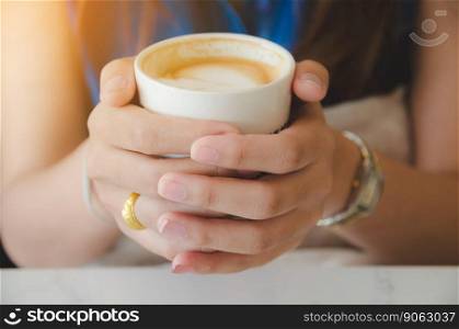 female hand holding white coffee cup