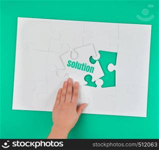female hand holding white puzzle with the word solution, process of closing the missing element, conceptual business background