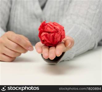 female hand holds a crumpled red ball of paper. New idea, brainstorming