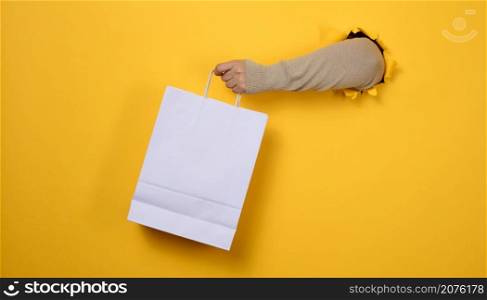 female hand holds a white paper disposable bag with handles for groceries and clothes. Recyclable packaging. Zero waste. Sale
