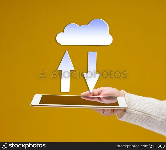 female hand holds an electronic gadget tablet on a yellow background, white cloud with arrows above it. Information exchange, data warehouse. Uploading a backup