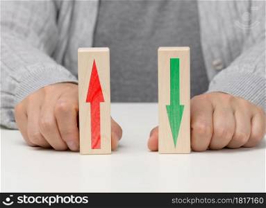 female hand holds wooden blocks with up and down arrows. The concept of lowering and increasing indices, exchange rates. Dynamics