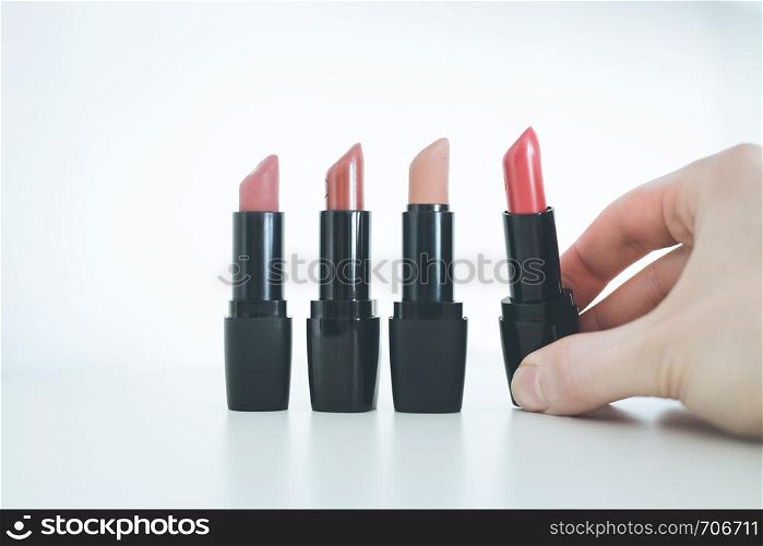 Female hand is taking a colourful red lipstick, elegant cosmetic products