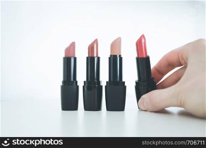 Female hand is taking a colourful red lipstick, elegant cosmetic products