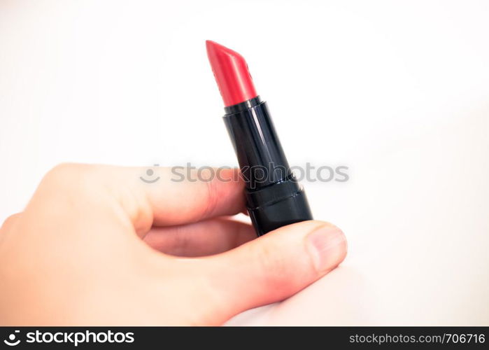 Female hand is taking a colourful red lipstick, elegant cosmetic products