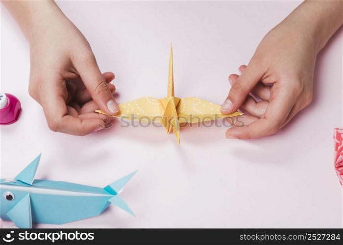 female hand made bird from origami paper pink backdrop