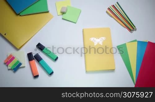 Female hand opening notepad on the white table with office tools