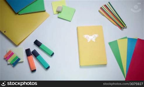 Female hand opening notepad on the white table with office tools