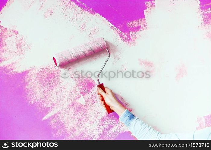 Female hand painting wall with paint roller. Close up of Decorator&rsquo;s hand painting wall with roller. copy space