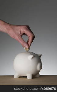 Female hand placing coin in piggy bank