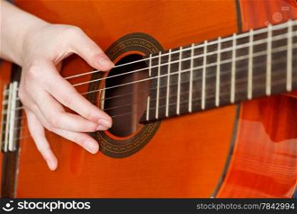 female hand playing acoustic guitar close up
