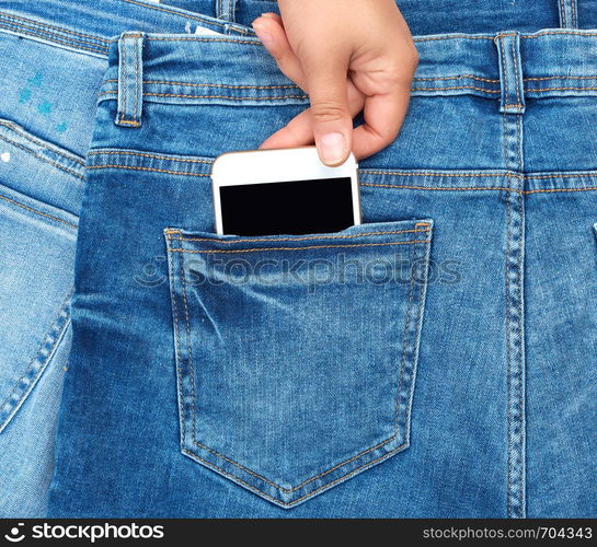 female hand pulls out of the back pocket of a blue jeans smartphone with a blank screen, full frame