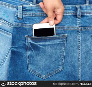 female hand pulls out of the back pocket of a blue jeans smartphone with a blank screen, full frame