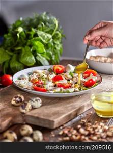 Female hand puts mustart sause to the plate of freshly cooked homemade salad from natural ingredients on a wooden table.. Woman pouring freshly cooked salad mustard sauce on a wooden board. Natural organic dieting food.