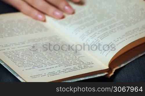 female hand shatters pages and show text of old book closeup