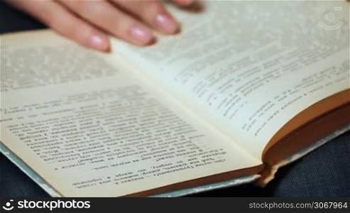 female hand shatters pages and show text of old book closeup