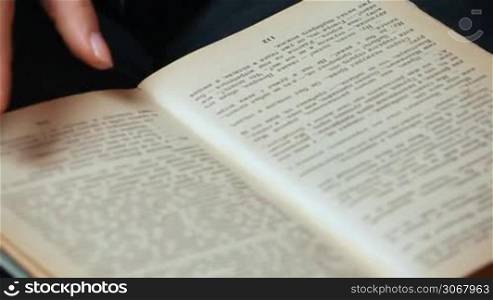 female hand shatters pages of old book with pictures closeup