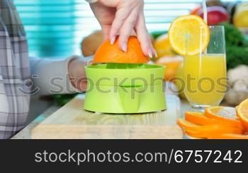 female hand squeezes orange juice on a juicer