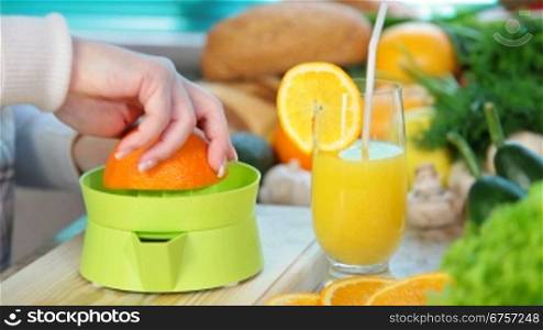female hand squeezes orange juice on a juicer