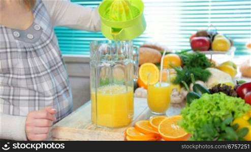Female hand squeezes orange juice on a juicer