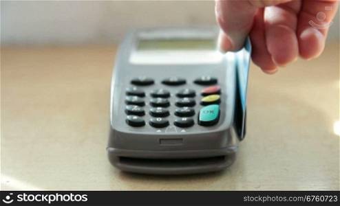 Female hand swiping a credit card through a credit card terminal