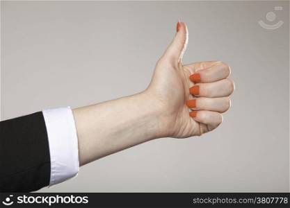 Female hand thumb up gesturing the all right symbol , ok sign gray background