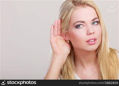 Female hand to ear listening on gray. Gossip girl with palm behind ear spying. Closeup young business woman listening secret.